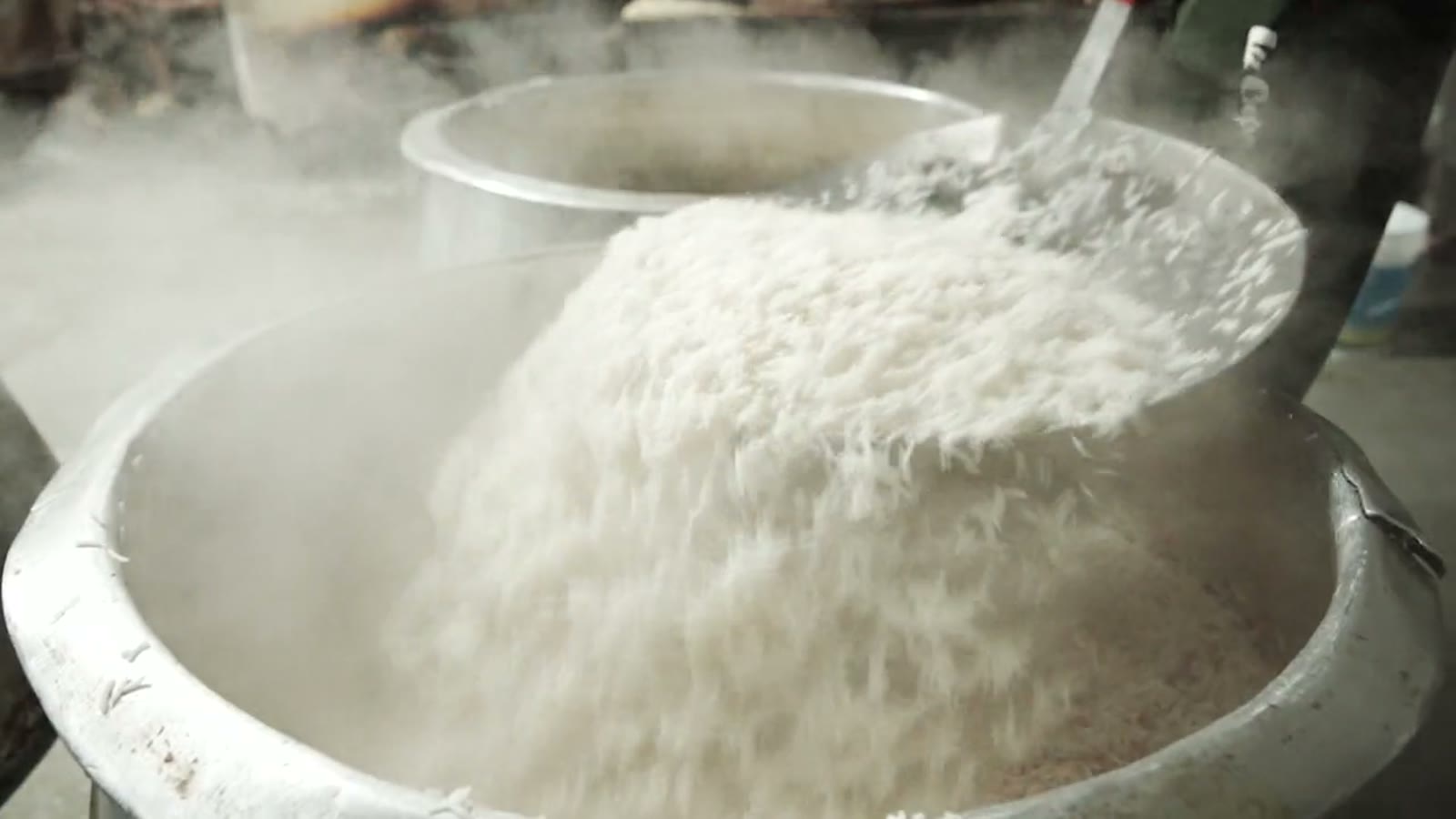 A vessel of biryani rice, steam rising off the surface