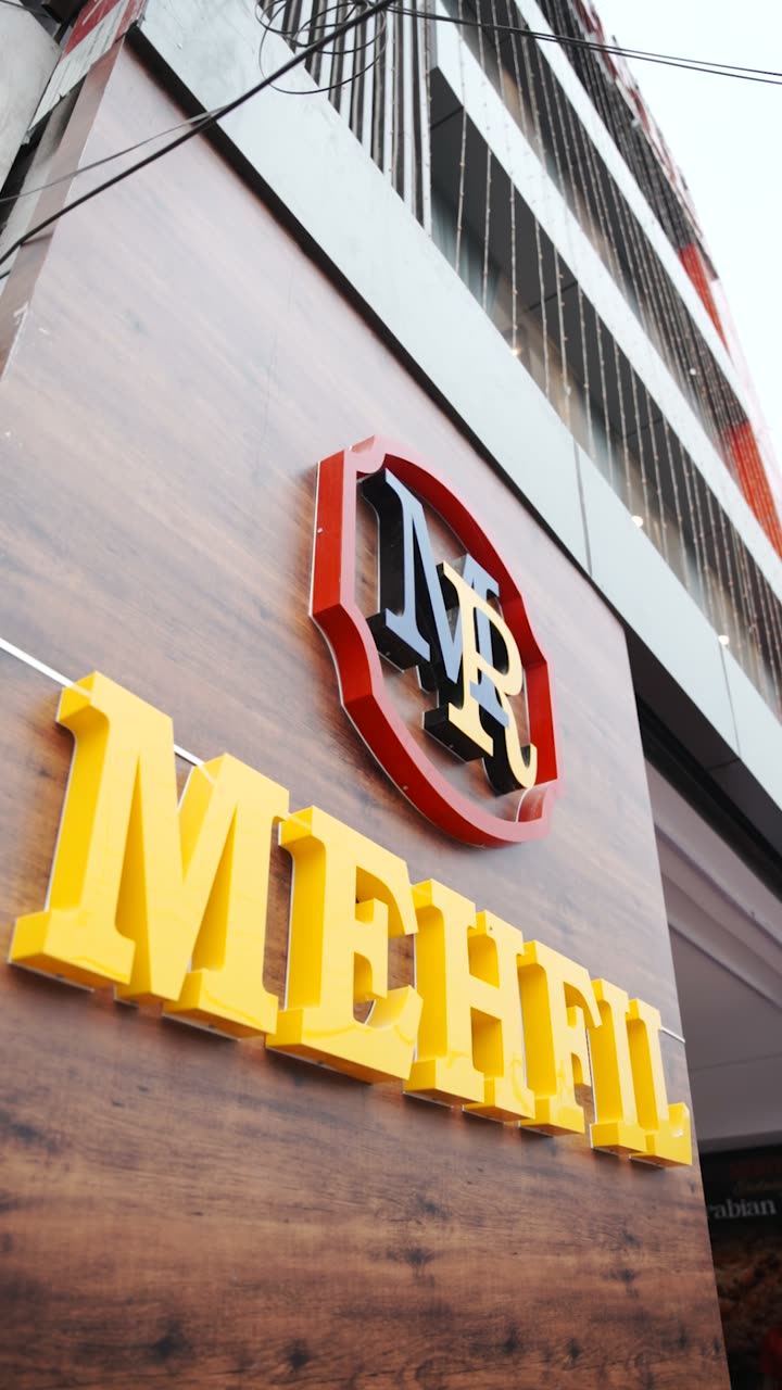 A Mehfil signboard, the crest and the name in yellow above a restaurant entrance